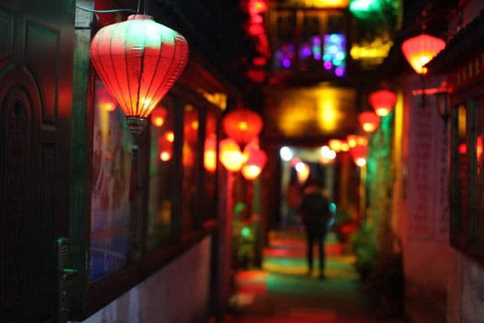 Una foto de la calle nocturna de un callejón iluminado por linternas de colores