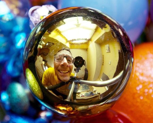 Una fotografía de un hombre visto en el reflejo de una chuchería navideña - Proyectos fotográficos para hacer con niños