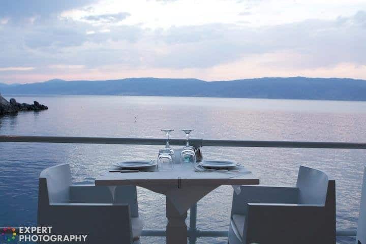 Una mesa puesta junto al mar al atardecer con una marca de agua de 'Fotografía experta' en la esquina inferior izquierda