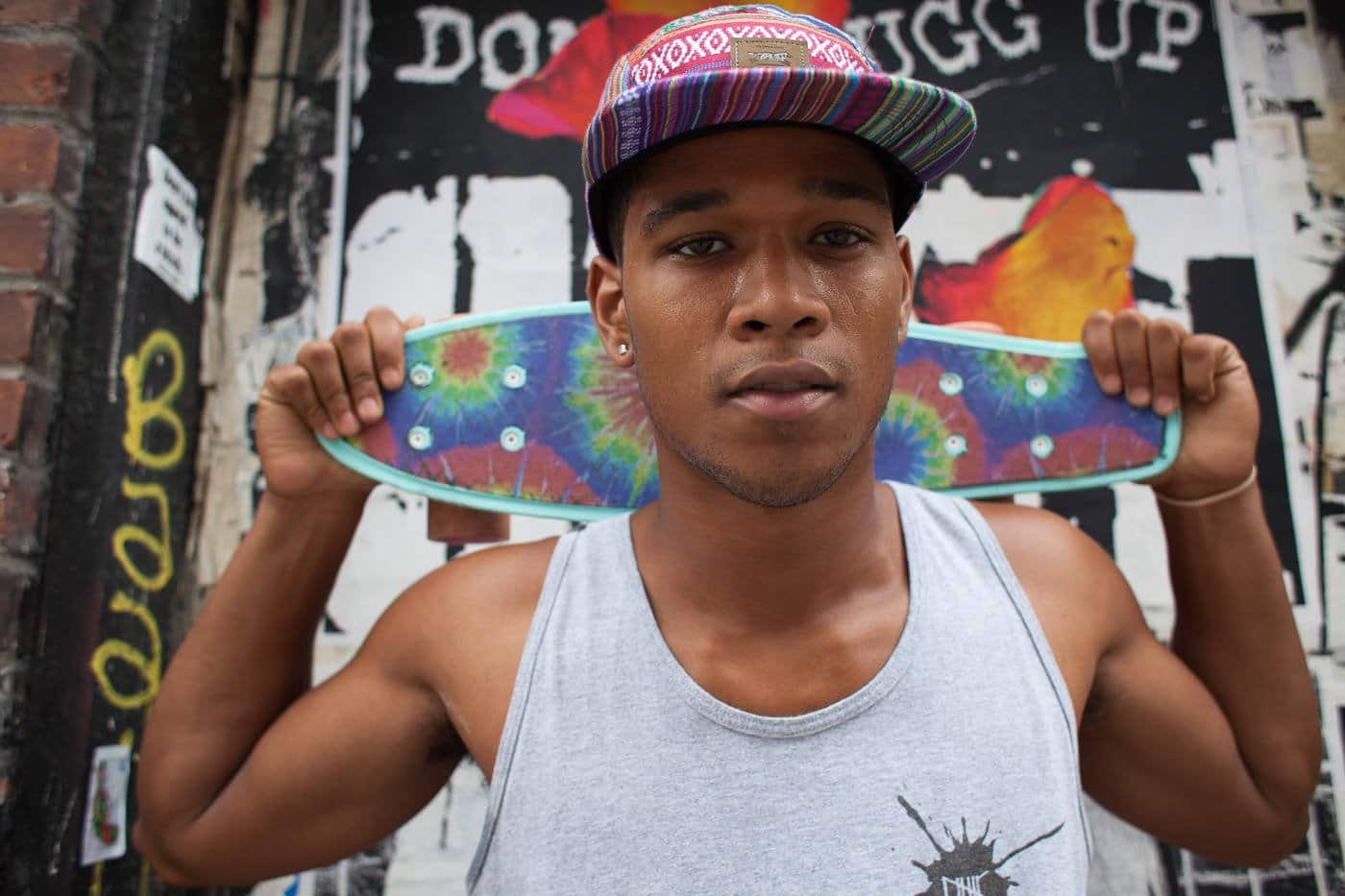 Fotografía callejera: Retrato de hombre joven con patineta detrás de la cabeza