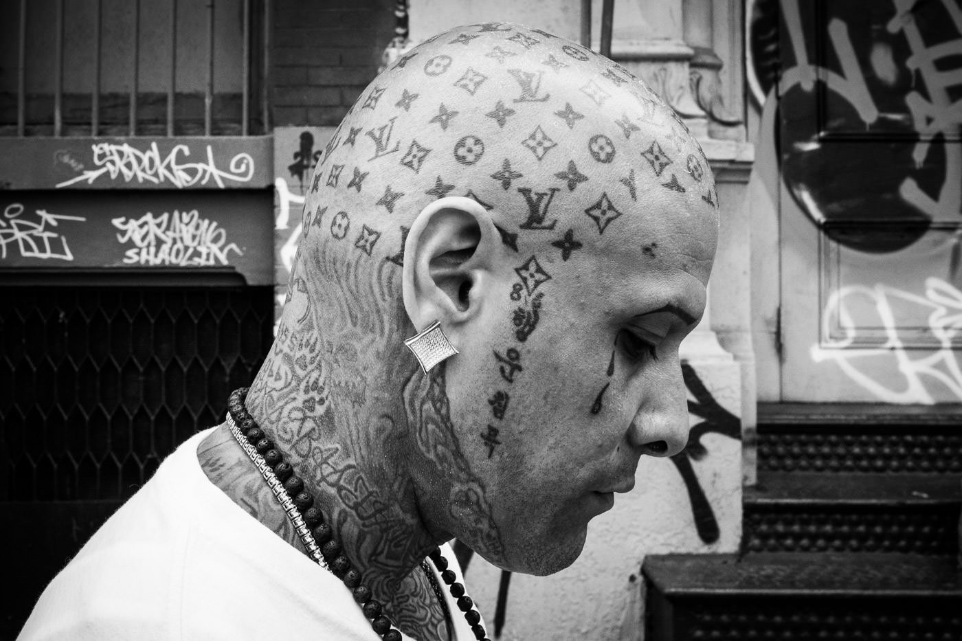 Fotografía callejera: retrato de un hombre de perfil que muestra elaborados tatuajes en la cabeza
