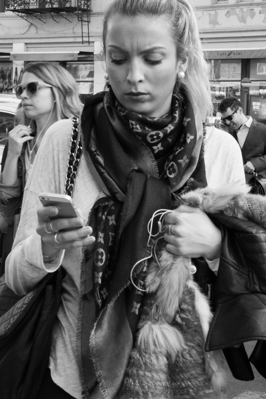 Fotografía callejera: retrato en blanco y negro de una mujer con cola de caballo revisando su teléfono