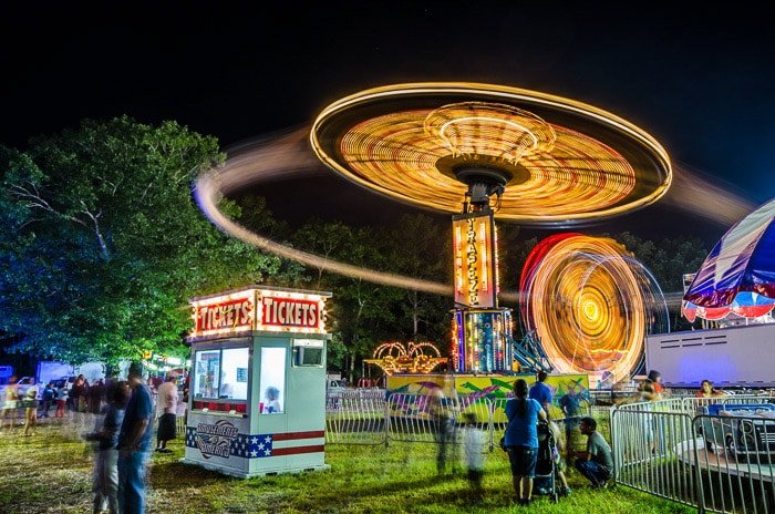 Una impresionante toma de fotografía nocturna de un parque de atracciones que demuestra los usos de la velocidad de obturación