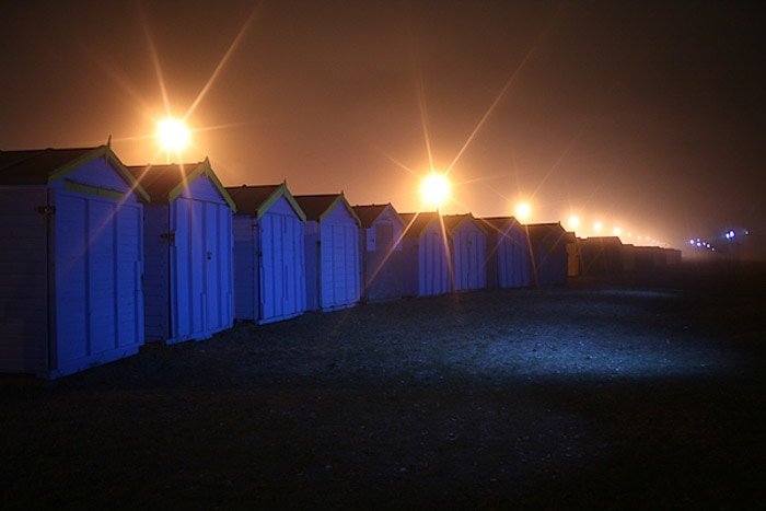 Una fotografía nocturna de una línea de pequeñas cabañas de madera.