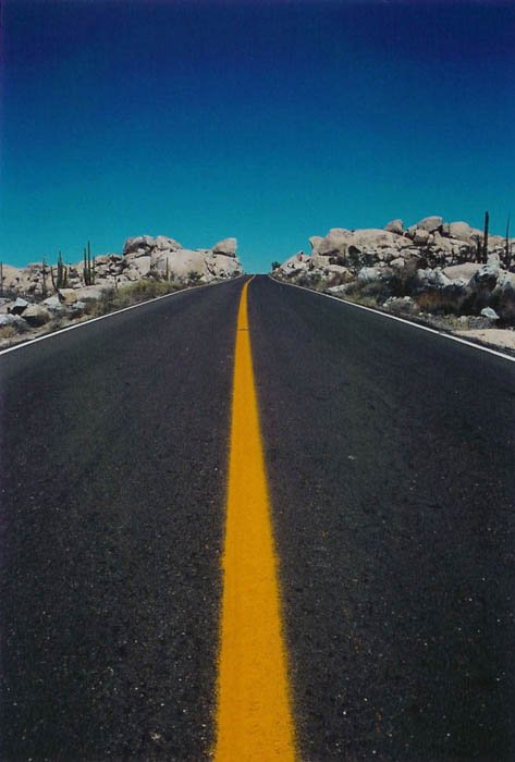 Foto de la carretera de una carretera que conduce al horizonte, el cielo azul y la carretera de rayas amarillas