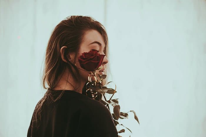 Fotografía de retrato de una niña sosteniendo una rosa por su rostro.  Consejos para la fotografía de autorretratos.
