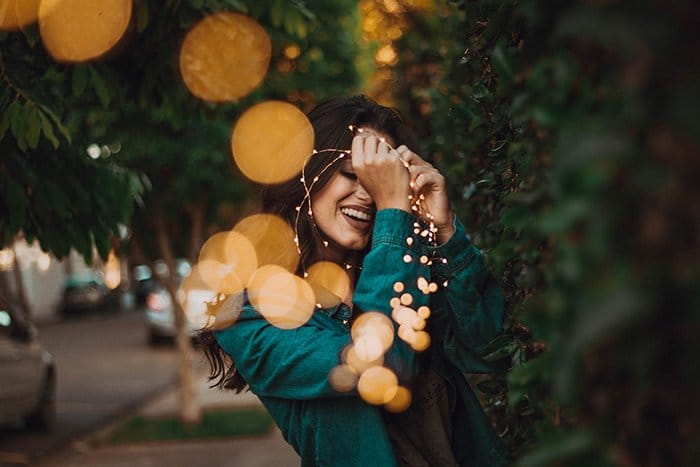 Retrato de ensueño de una niña con luces de colores junto a los arbustos.  Consejos para la fotografía de autorretratos.