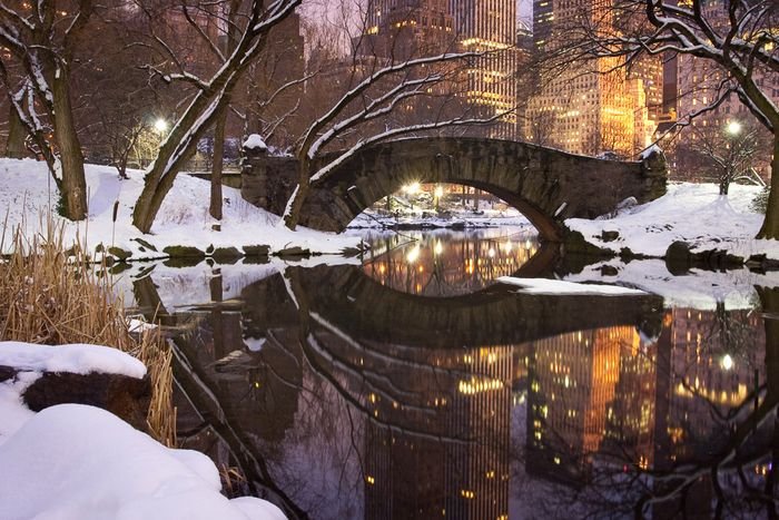 Un puente cubierto de nieve sobre un río en el primer plano de un paisaje urbano 