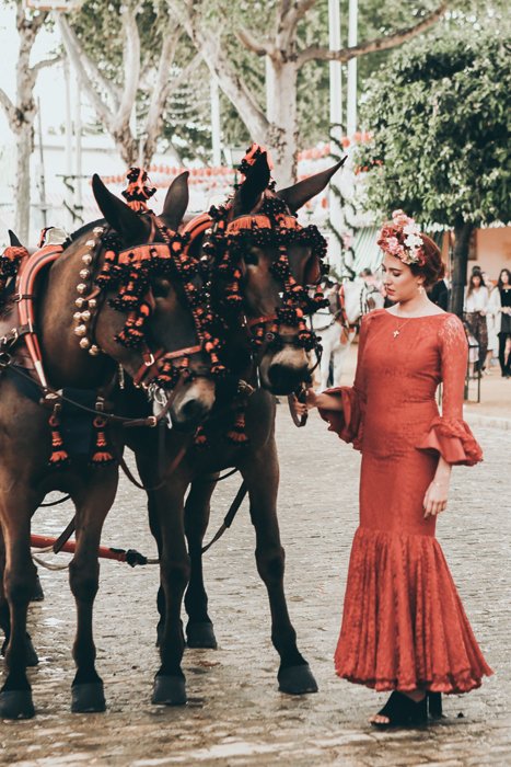 Una mujer en Fancy Dress acariciando a dos caballos disfrazados