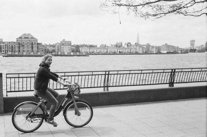 Toma en blanco y negro de una niña en bicicleta por un río, tomada con la cámara vintage Rollei B35