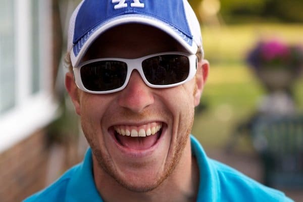 Retrato de un joven con gafas de sol y gorra de béisbol, demostrando la técnica de fondo suave en fotografía