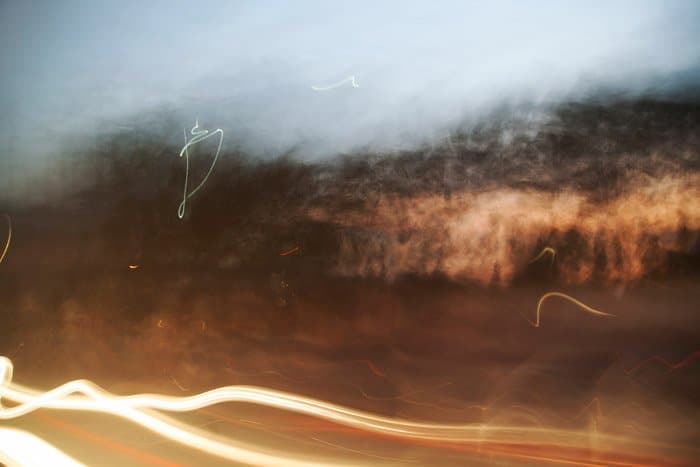 Fotografía de obturación lenta de estelas de luz borrosas y arbustos.  tomada mientras viajaba por una carretera al anochecer.  Ideas de fotografía abstracta.