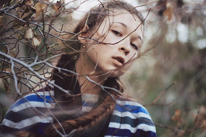 Retrato de una niña de cabello oscuro con un fondo de bosque borroso. 