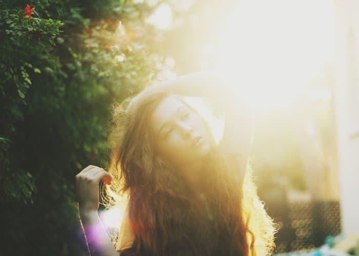 Retrato lleno de luz de ensueño de una chica de cabello oscuro con un fondo de bosque borroso.