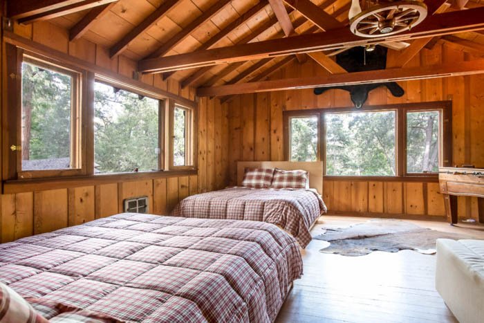 foto interior de una cabaña con dos camas y grandes ventanales