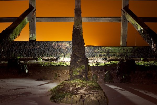 Una foto impresionante de un cielo naranja en el fondo de una estructura de madera: consejos para pintar con luz