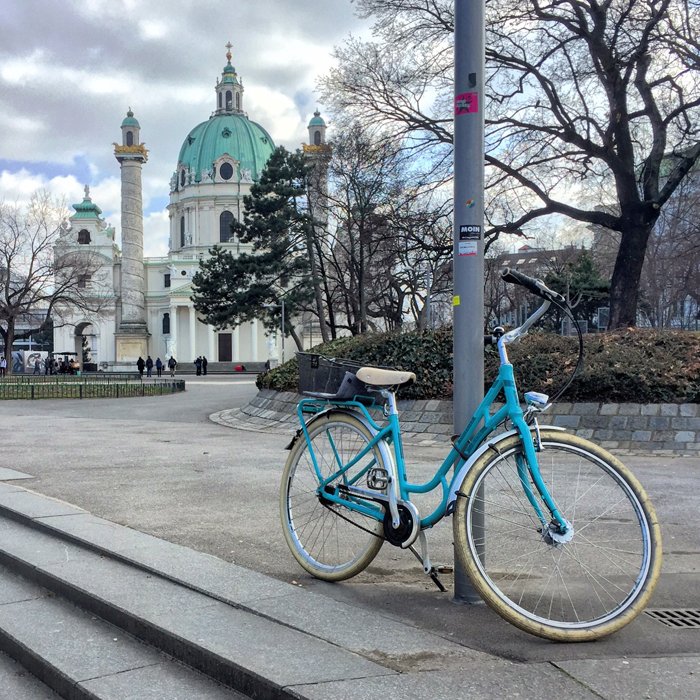 Foto de una bicicleta turquesa con una iglesia al fondo