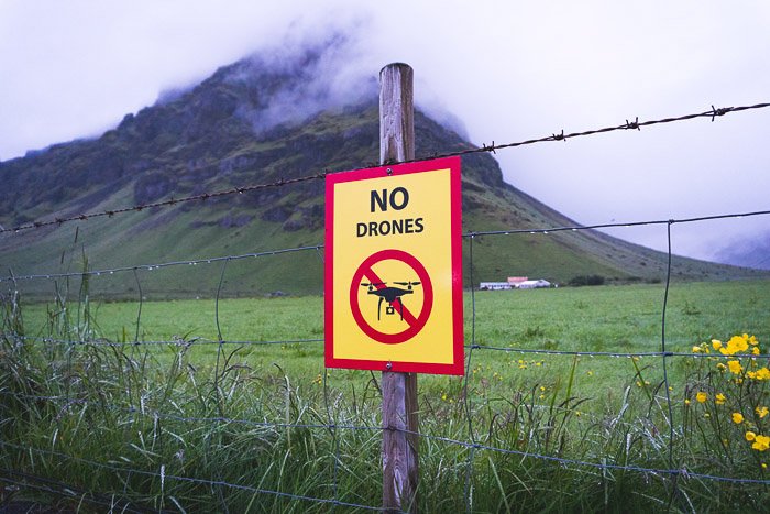 Un letrero que dice que no hay drones en un paisaje verde.