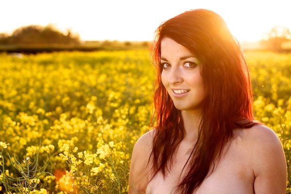 Foto de una mujer joven en el campo de flores amarillas demostrando la edición con contraste
