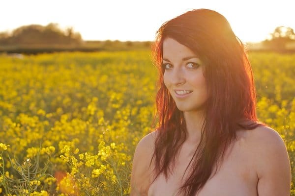 Foto de una mujer joven en el campo de flores amarillas demostrando la edición con reflejos