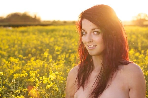 Foto de una mujer joven en el campo de flores amarillas demostrando la edición con vitalidad