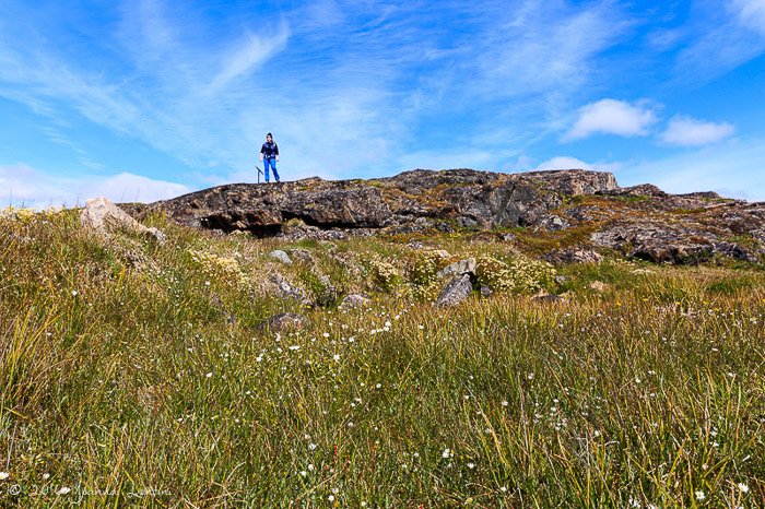 Una fotógrafa de pie sobre una roca en un día despejado - equipo de fotografía de aventuras