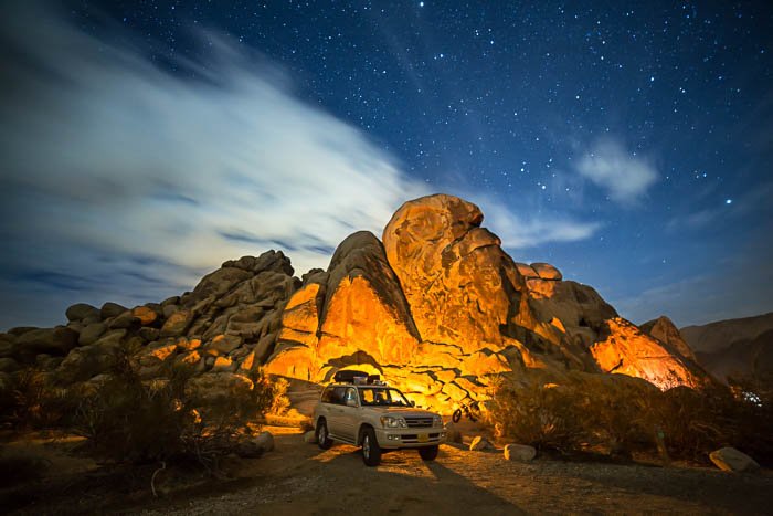 Imagen en el Parque Nacional Joshua Tree en California, que muestra un automóvil blanco frente a rocas altas.