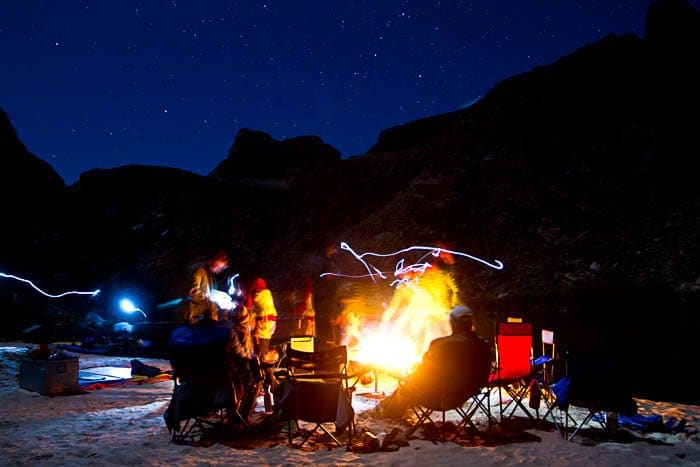 Foto de personas alrededor de una fogata, que muestra la vida del campamento durante la fotografía al aire libre