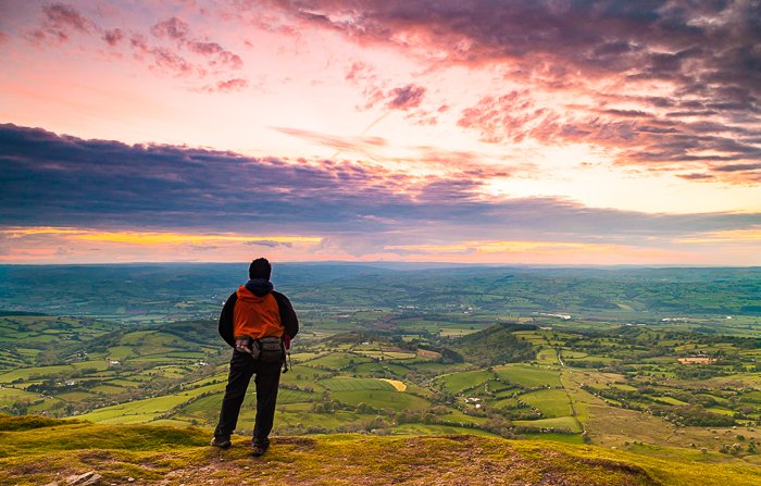 un excursionista que admira la puesta de sol desde un paisaje exuberante: habilidades de fotografía de aventuras