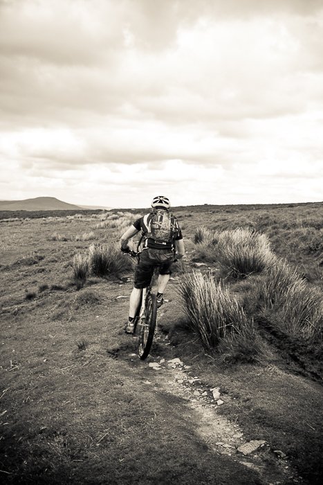 Disparo monocromo de un ciclista moviéndose a través de un paisaje - habilidades de fotografía de aventuras