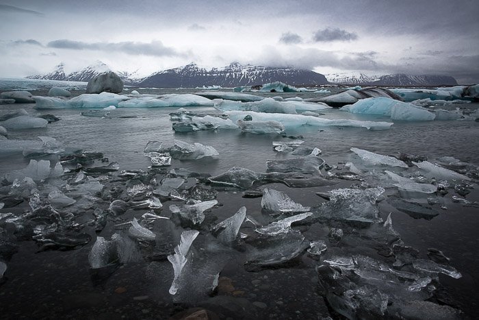 Imagen de paisaje de río de hielo con trozos de hielo congelado flotando en él y montañas en la distancia, tomada en Islandia