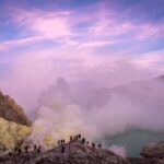 Foto de personas de pie sobre un acantilado con el hermoso cielo púrpura arriba