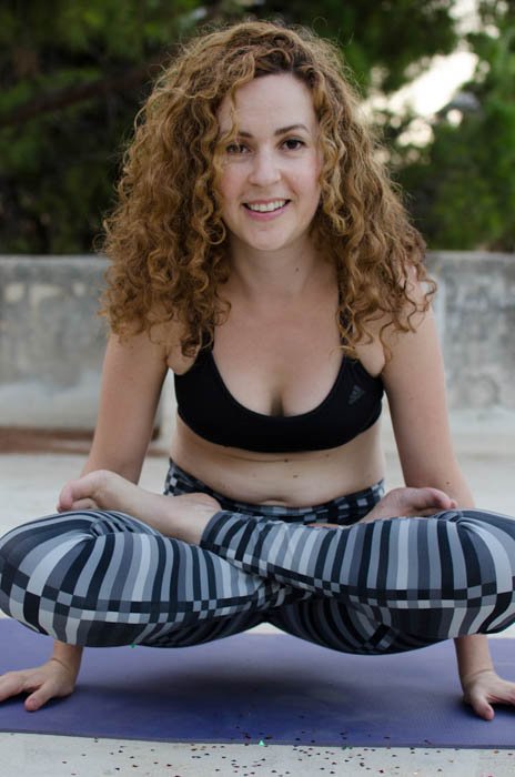 Fotografía de yoga que muestra un modelo en una pose de equilibrio de brazos, mirando directamente a la cámara