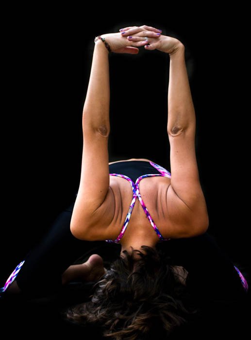 Foto de un yogini en una pose inclinada hacia adelante, que muestra el uso creativo del fondo negro en la fotografía.