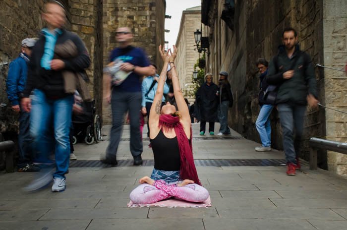 el modelo está centrado y con un enfoque nítido en una pose de yoga sentado mientras las personas a su alrededor están borrosas 