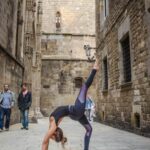 niña realizando pose de rueda de yoga con una sola pierna en la calle