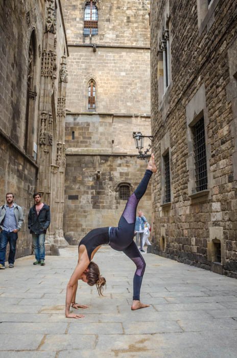 niña realizando pose de rueda de yoga con una sola pierna en la calle