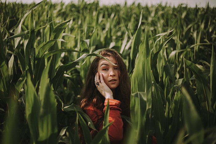 Retrato de una niña posando en la hierba alta con luz ambiental de día nublado