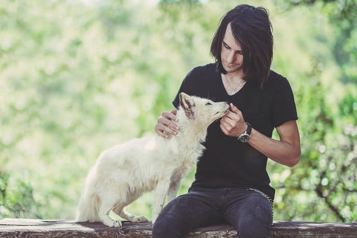 Dulce retrato al aire libre de un hombre con un perro blanco: apertura para fotografía de mascotas