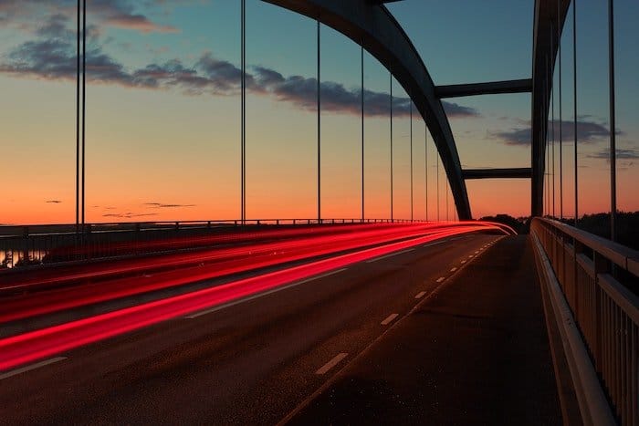 una racha de luces traseras sobre un puente fotografiado con poca luz