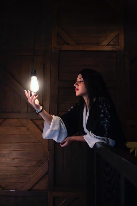 idea de fotografía con poca luz: una sola bombilla ilumina el retrato de una mujer 