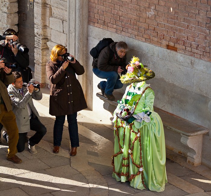 Una multitud fotografiando una exhibición de carnaval de disfraces verdes 