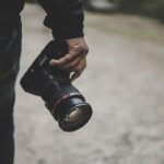 fotógrafo sosteniendo la cámara réflex digital de fotograma completo más barata a su lado