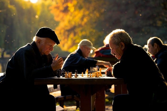 Sincero retrato de dos hombres jugando al ajedrez en un parque