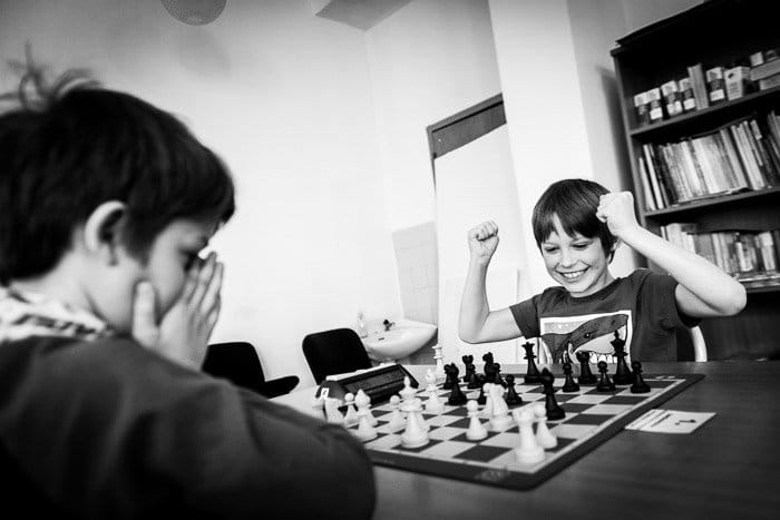 Retrato monótono de dos niños jugando al ajedrez al aire libre