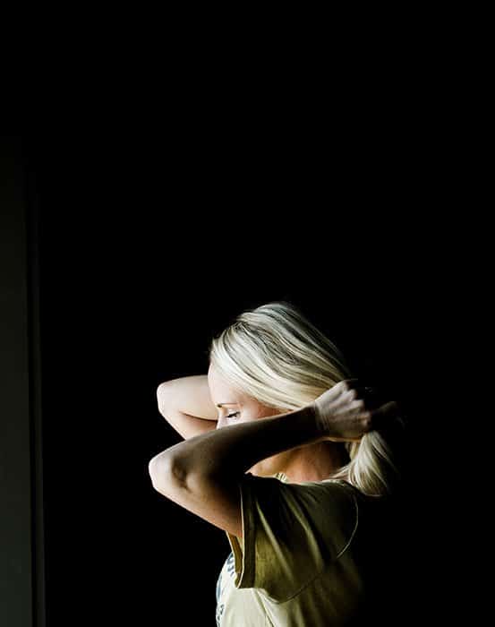 Retrato atmosférico de una modelo femenina sosteniendo su cabello, filmada con iluminación de claroscuro