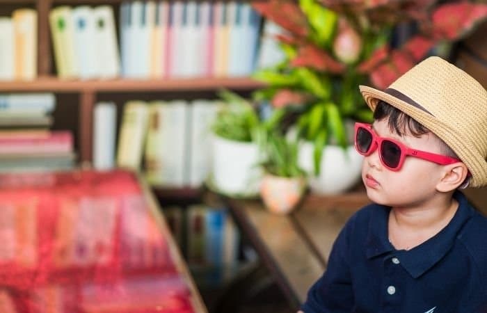 Fotografía infantil sincera de un niño con un sombrero veraniego y gafas de sol.