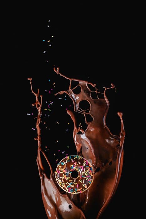 Fotografía de comida creativa de una dona frente a un toque de chocolate