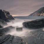 Foto de larga exposición de las rocas y las olas en la costa de Porto Venere al amanecer.