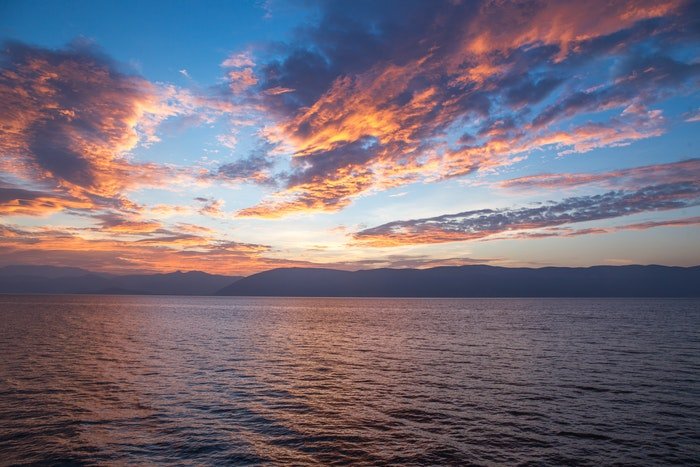 foto de nubes y puesta de sol sobre un enorme paisaje acuático